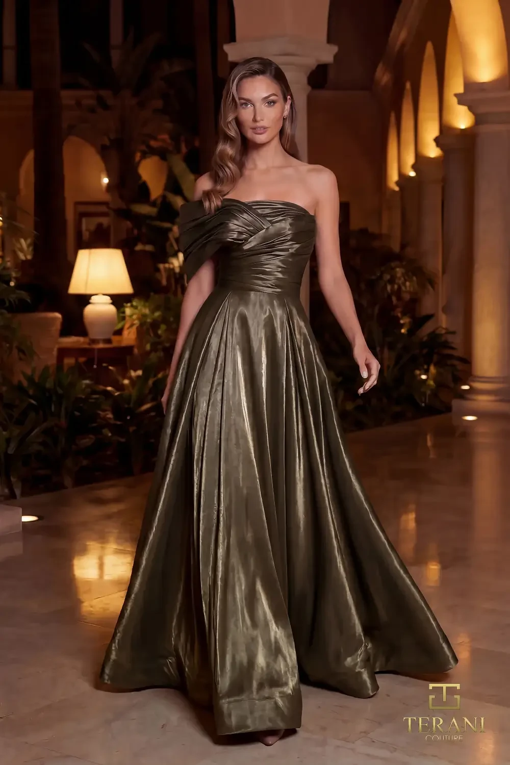A woman wearing an elegant olive green strapless gown in a beautifully lit interior setting.