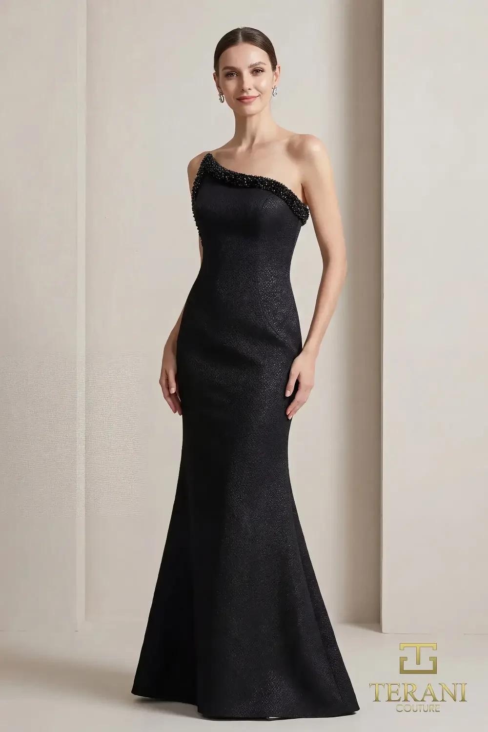 A woman in a sleek, one-shoulder black evening gown with a fitted silhouette and a mermaid bottom, posed elegantly against a light backdrop.