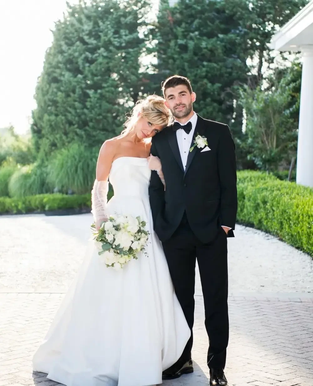 Сouple wearing a white gown and a black suit at home